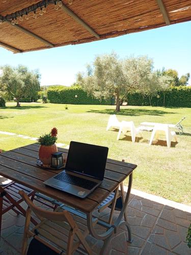a laptop computer sitting on a wooden table on a patio at "IL CASALE DEI GIRASOLI" Country House in Capalbio in Capalbio