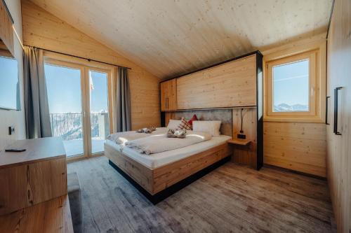 a bedroom with a bed in a room with windows at Sonna Hüsli Lodge in Tschagguns