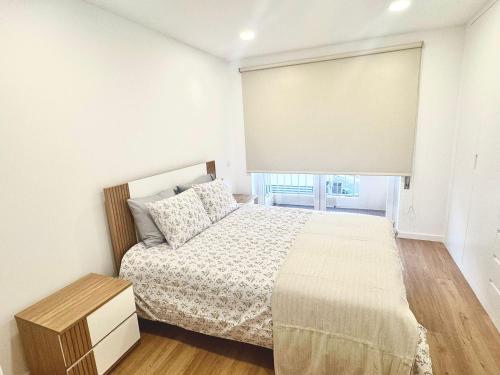 a white bedroom with a bed and a window at Figueira Luxury Comfort House in Figueira da Foz