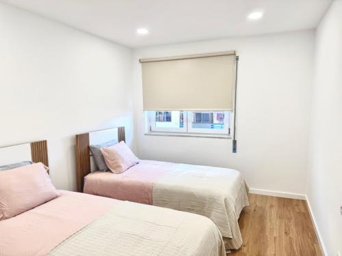 two beds in a room with a window at Figueira Luxury Comfort House in Figueira da Foz