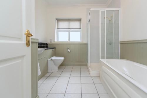 a bathroom with a tub and a toilet and a shower at Grianán in Ballyconneely