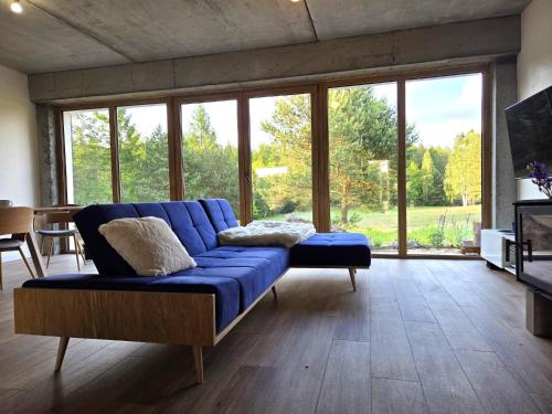 a blue couch in a living room with a large window at Warmińska Polana - Nowy, całoroczny dom na 2 ha łące dla 8 osób - Gietrzwałd in Gietrzwałd