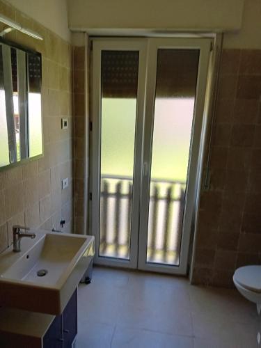 a bathroom with a sink and a sliding glass door at Riva Apartment Negrelli in Riva del Garda