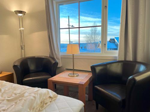 a bedroom with two chairs and a bed and a window at Bitihorn fjellbris in Beitostøl