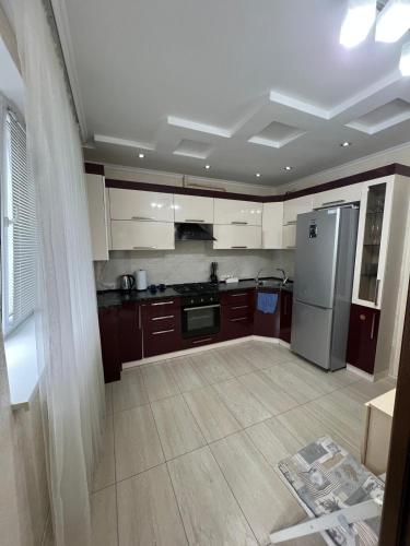 a kitchen with brown cabinets and a stainless steel refrigerator at Spacious Modern Apartment mins drive to City Center in Chişinău