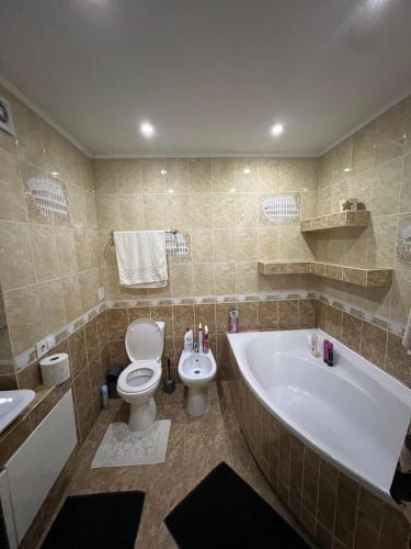 a bathroom with a tub and a toilet and a sink at Spacious Modern Apartment mins drive to City Center in Chişinău