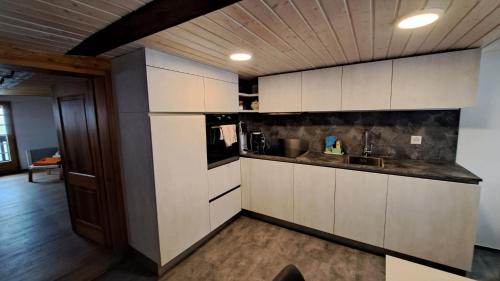 a kitchen with white cabinets and a sink at Chalet Bernadette in Mörel
