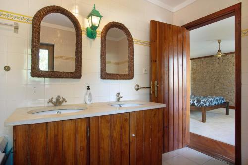a bathroom with two sinks and two mirrors at Melquites Country House in Barrantes