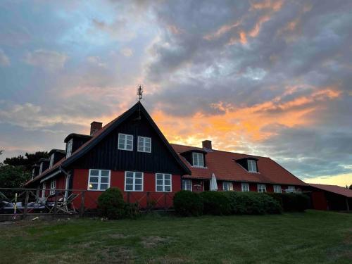 a red house with a black roof with a sunset in the background at Wildernest Bornholm - Svanen in Neksø
