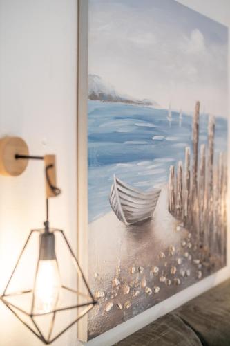 a lamp next to a painting of a boat on the beach at SKYROS AVRA Residences in Skiros