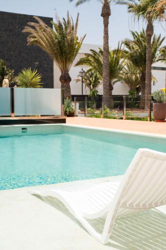 a white chair sitting next to a swimming pool at TINDAYA by Buenavilla in Puerto Calero