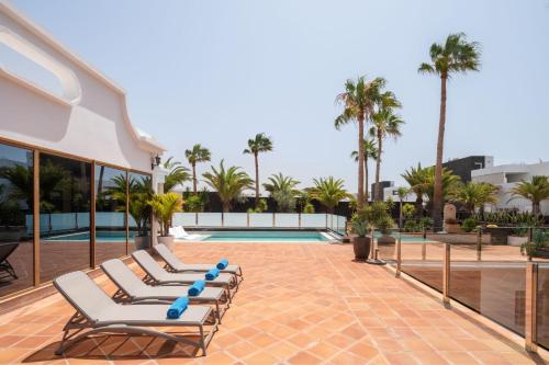 a row of lounge chairs next to a swimming pool at TINDAYA by Buenavilla in Puerto Calero