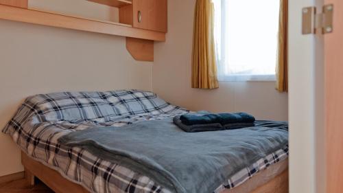 a small bed in a room with a window at Domki Nad Morzem IDPB in Gąski