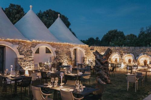 Una carpa con mesas y sillas frente a un edificio de piedra. en MASSERIA OSHA ex QUIS UT DEUS, 