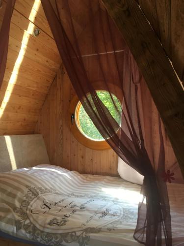 a bed in a wooden room with a window at Roulottes des Combrailles in Saint-Pardoux