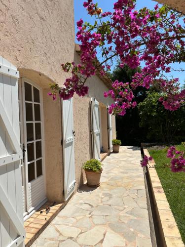 un bâtiment avec un arbre et des fleurs roses dans l'établissement Villa Hass, à Mandelieu-la-Napoule