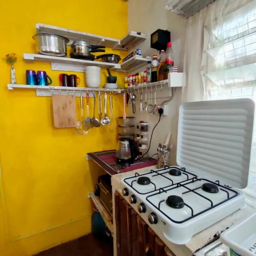 a kitchen with a stove and a yellow wall at Palm Sunrise in Diani Beach