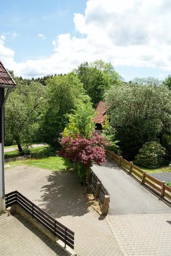 a fence next to a walkway with flowers and trees at Hotel Braunlage in Braunlage