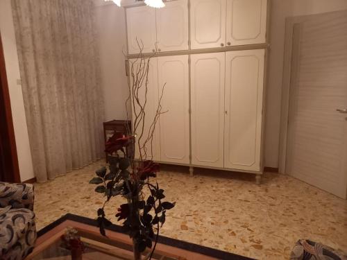 レヴェラーノにあるCasa Indipendente MARGHERITAの白いキャビネットと植物の入った花瓶のある部屋
