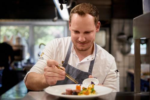 a man in a kitchen eating a plate of food at Relais & Châteaux Hotel Tennerhof in Kitzbühel