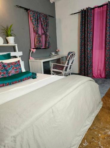 a bedroom with a bed with a desk and a chair at Palm Sunrise in Diani Beach