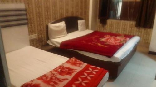 a small room with two beds and a chair at A budget hotel sheeva palace near tulshi chowk in Haridwār