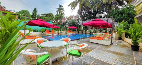 坎多林Maashpi Hotel & Resort, Candolim的带桌椅和游泳池的露台