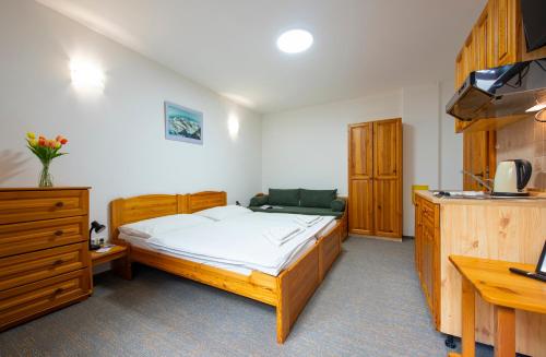 a bedroom with a large bed and a desk at Penzion Snezienka in Tatranská Lomnica