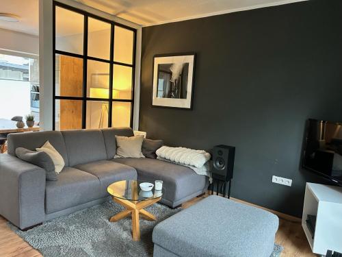 a living room with a gray couch and a table at stilvolles Ferienhaus mit Garten im Ortskern von Olsberg in Olsberg