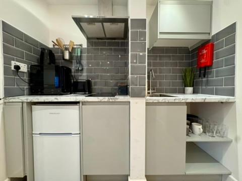 a kitchen with white cabinets and a brick wall at Canal Walk Studio Apartments in Southampton