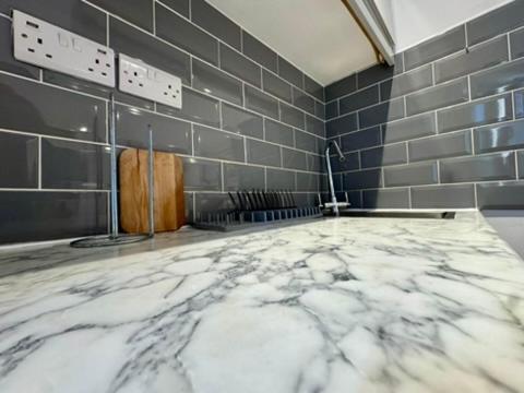 a bathroom with a marble floor and gray tiled walls at Canal Walk Studio Apartments in Southampton