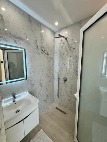 a white bathroom with a sink and a shower at Villa e Diellit in Kaninë