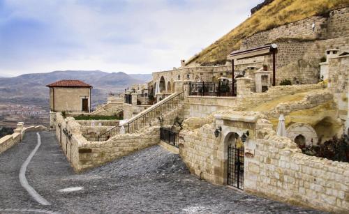 an old stone building with a mountain in the background at Kayakapi Premium Caves Cappadocia in Urgup