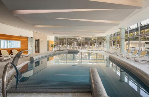 a large swimming pool with chairs in a building at Bluesun Hotel Elaphusa in Bol