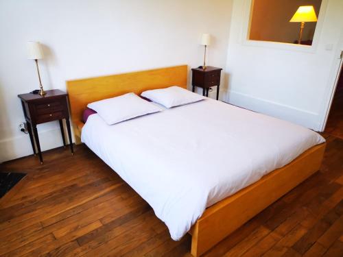 une chambre avec un grand lit blanc avec deux tables de nuit dans l'établissement Les Carrés, à Versailles