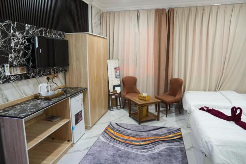 a hotel room with two beds and a tv and a kitchen at hotel rose garden فندق روز جاردن in Duqm