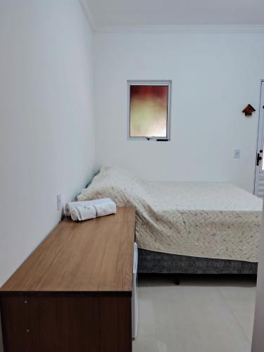 Un dormitorio con una cama y una mesa de madera. en Suíte Da Rosa, en Cachoeira Paulista