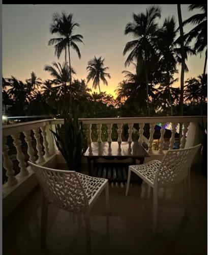 a table and chairs on a balcony with palm trees at White House Beach Apartments in Mandrem