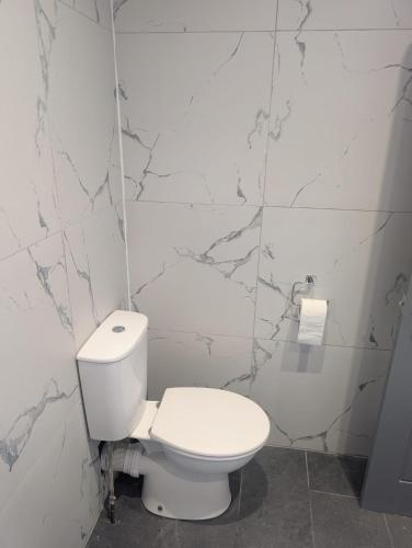 a bathroom with a white toilet and marble walls at Cleethorpes Apartments - Serviced accommodation in Grimsby