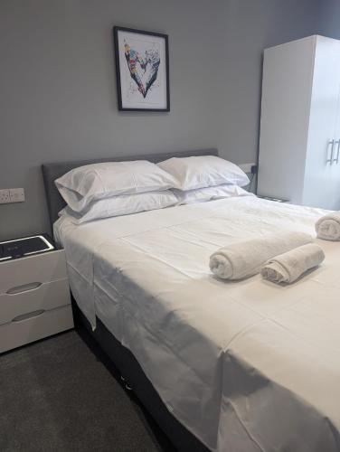 a large white bed with two towels on it at Cleethorpes Apartments - Serviced accommodation in Grimsby