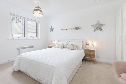 a white bedroom with a white bed and a window at 5 Parc Delfryn in Benllech