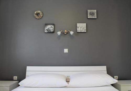 a bedroom with a white bed with four pictures on the wall at Apartmani Marin in Vrbnik
