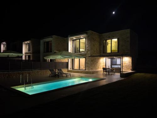 a house with a swimming pool at night at The Olive Path in Kalandra
