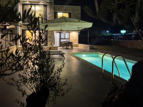 a swimming pool at night with an umbrella at The Olive Path in Kalandra
