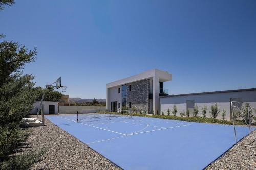 a tennis court in front of a building at Manza Villa in Sfakaki