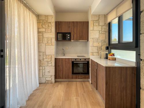 a kitchen with wooden cabinets and a stone wall at The Olive Path in Kalandra