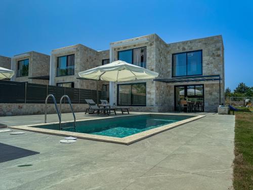 a house with a swimming pool and an umbrella at The Olive Path in Kalandra