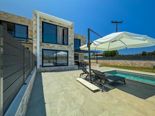 a patio with two chairs and an umbrella next to a pool at The Olive Path in Kalandra