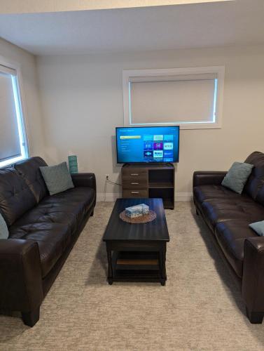 a living room with two couches and a flat screen tv at Spacious Luxury walk out Basement in Kitchener
