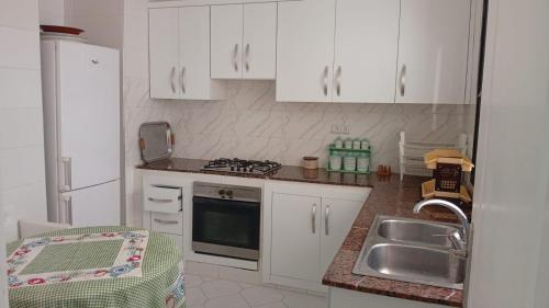 una cucina con mobili bianchi e un lavandino di Marina smir a Marina Smir